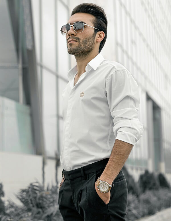 Man wearing a white shirt with black pants, sunglasses, and a watch.